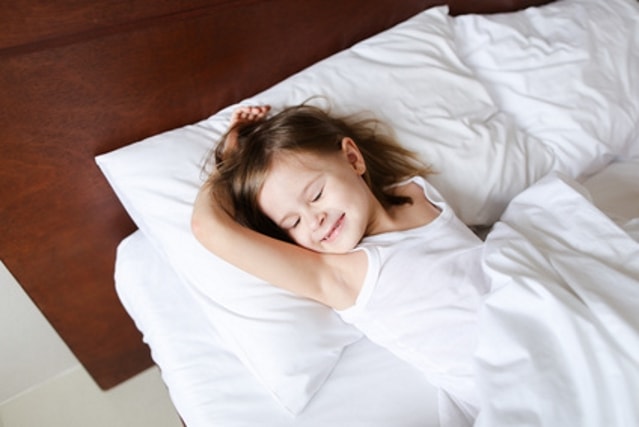 Kind liegend im Bett mit Bettdecke